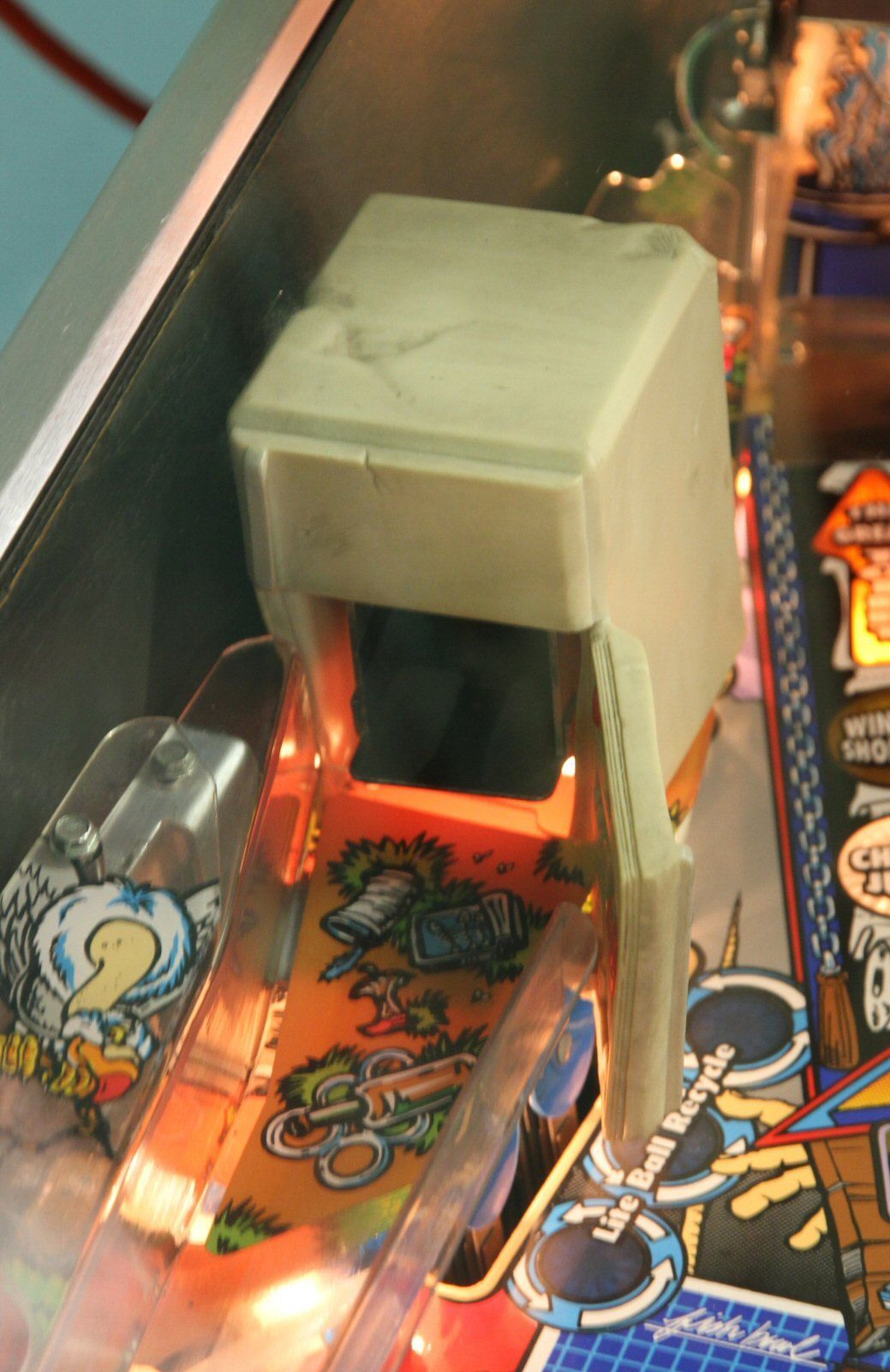 The white refrigerator toy on the left side of the playfield, lit from inside, with a small ramp in front.